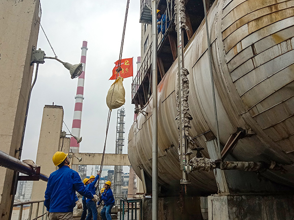 5月10日中午，在動(dòng)力車(chē)間三期工藝除氧器地面，黨員突擊隊(duì)隊(duì)員用滑輪往工藝除氧器平臺(tái)運(yùn)送鋼絲網(wǎng)，用以纏繞新填料.jpg